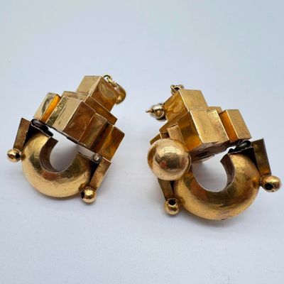 paire de boucles d'oreilles dorées ornées de motifs géométriques sur fond blanc