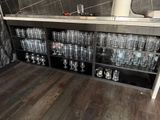 bottles and glasses on a shelf in a room with a tiled wall