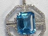 un gros plan d'un pendentif en pierre bleue et diamants posé sur une surface blanche