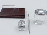an image of a desk set with a pen, inkwell, and glass container