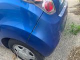 a small blue car that has been damaged and is parked on the side of the road
