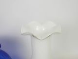 a white vase sitting on a table next to a blue vase
