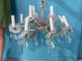 a woman standing next to a chandelier that is hanging from a wall