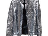 une veste à paillettes argentées suspendue à un cintre sur un mur blanc