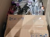 a cardboard box full of assorted items in the corner of a room