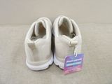 white sneakers with a tag attached to them sitting on a couch
