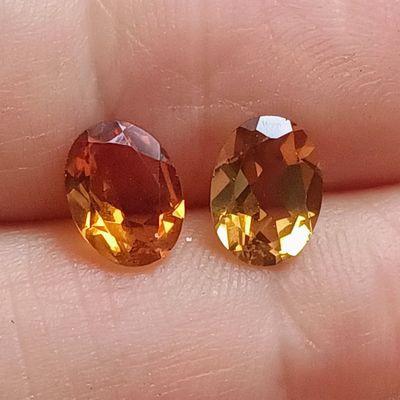 une paire de pierres précieuses jaunes et orange posées sur le doigt d'une personne