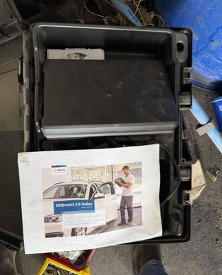 une photo d'un homme debout à côté d'un carton sur lequel figure l'image d'une voiture