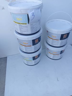 several buckets of paint sitting on top of a table next to a wall