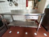 a stainless steel table in a kitchen with a stove in the background