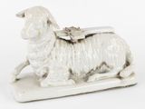 a white sheep figurine with a saddle on its back