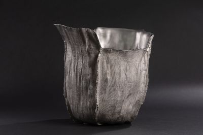 a close up of a silver vase on a black background