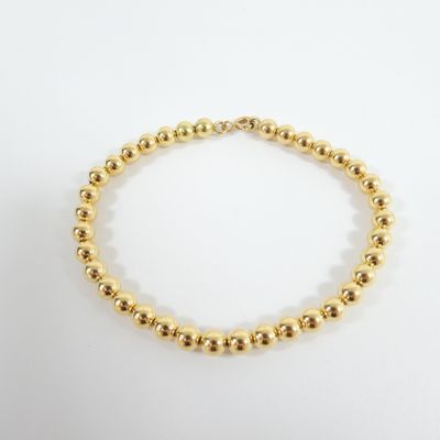 a gold beaded bracelet on a white background
