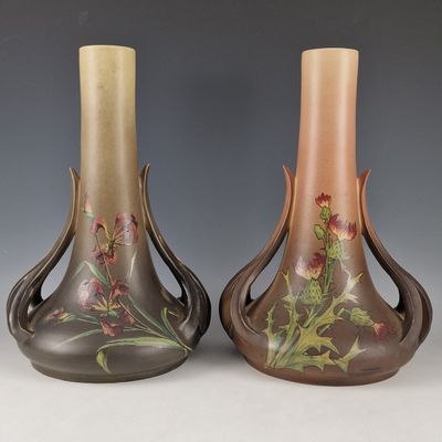 pair of vases with floral designs on them sitting on a table