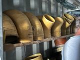 a man standing in front of a shelf full of wooden vases