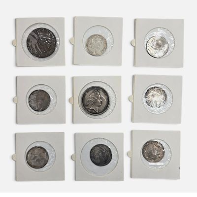 six types différents de pièces d'argent dans une boîte posée sur une surface blanche