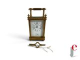 une petite horloge avec une clé posée devant
