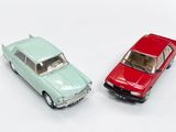 two toy cars sitting next to each other on a white surface