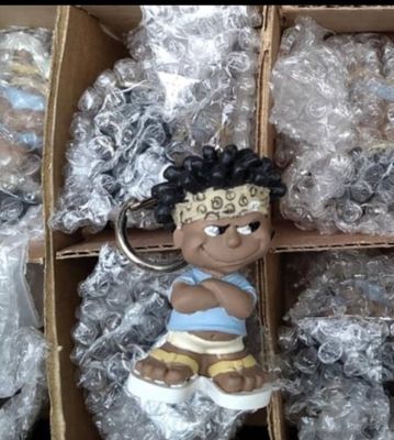 un petit porte-clés représentant un garçon avec un bandeau, dans une boîte en carton