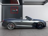 a grey sports car parked in a garage with the top down