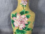 un vase jaune orné de fleurs roses et de feuilles vertes