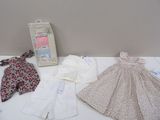 une table blanche sur laquelle sont posés des vêtements pour bébé et un cadre photo
