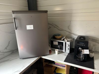 a small kitchen with a silver refrigerator and a coffee maker on the counter