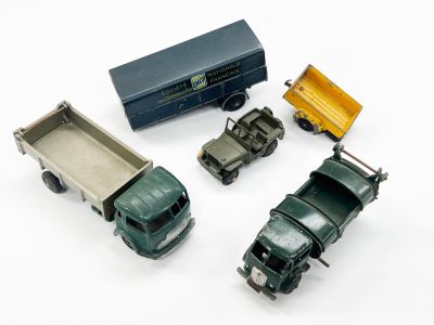 quatre camions miniatures et une boîte posés sur une surface blanche