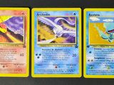 trois cartes Pokémon posées sur une table avec un fond noir