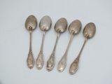 six silver spoons are lined up in a row on a white surface