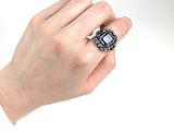 une personne tenant une bague sertie d'une pierre bleue