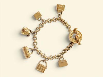 a gold bracelet with charms on it on a white surface