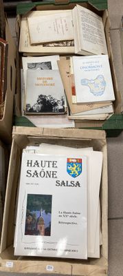 Plusieurs cartons remplis de livres sont empilés les uns sur les autres par terre.