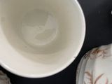 a white cup with a brown design on it