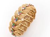 a close up of a gold bracelet with multi colored stones