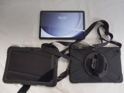 a camera and a tablet on a bed with a strap