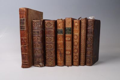 several old books are stacked on top of each other on a white surface