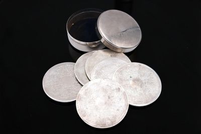 a pile of silver coins sitting on a black surface