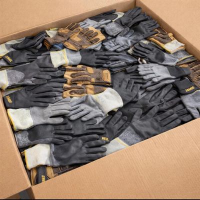 de nombreuses paires de gants dans une boîte posée par terre