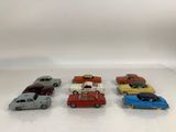 six toy cars are lined up in a row on a white surface