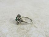an image of a diamond and emerald ring on a marble surface