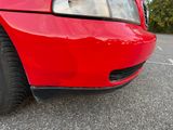 a red car parked in a parking lot with trees in the background
