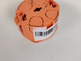 un objet en plastique orange portant un code-barres, posé sur une surface blanche