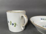 pair of porcelain cups and saucers with blue flowers on them