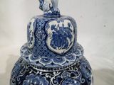 un vase bleu et blanc surmonté d'un oiseau