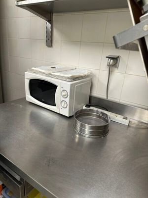un micro-ondes posé sur un plan de travail en métal dans une cuisine