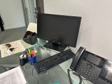 a desk with a computer, phone, telephone, and other office supplies on it