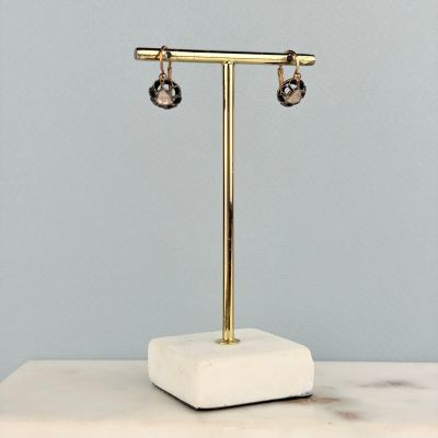 une paire de boucles d'oreilles posée sur un présentoir, sur une table en marbre