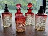 quatre flacons de parfum posés sur une table près d'une fenêtre