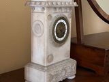une horloge posée sur une commode, avec un miroir en arrière-plan